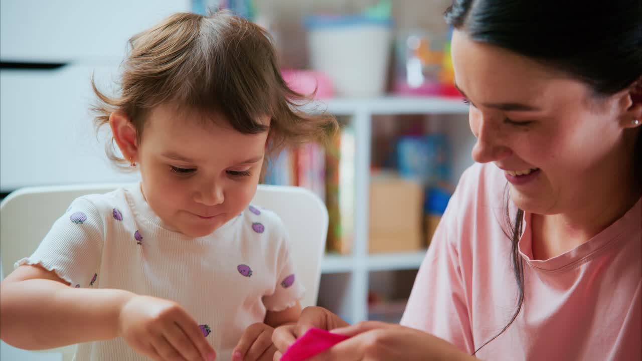 A Heartwarming Moment: A Young Girl Joyfully Engages with Her Mother while Admiring a Small Animal in a Playful and Nurturing Environment