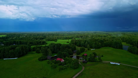 Reveladora-Vista-De-Drones-De-Una-Exuberante-Granja-Verde-Y-Un-Bosque-Con-Un-Cielo-Azul-Profundo