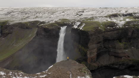 Antena:-Una-Persona-Con-Chaqueta-Amarilla,-Mirando-La-Cascada-De-Haifoss