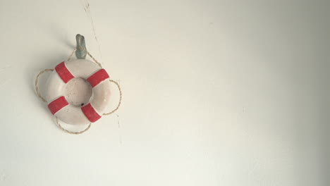 a miniature lifebuoy hanging on a wooden wall in a seaside cabana