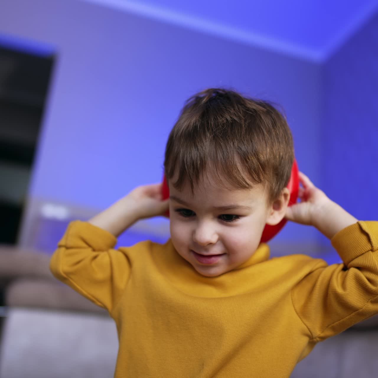 Cute toddler with brown hair wearing yellow sweater. Little boy holding a red ring from pyramid behind his head. Low angle view