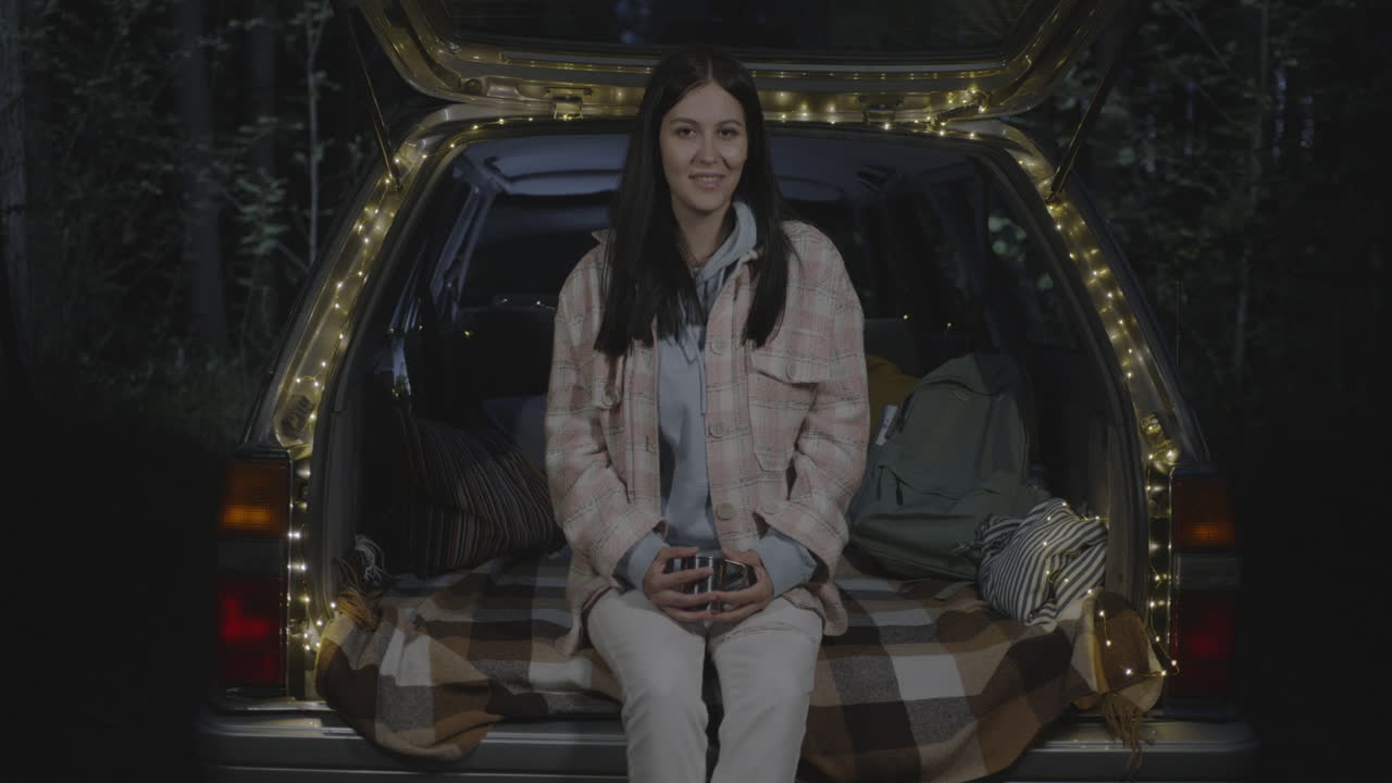 Woman relaxing in a car trunk at night