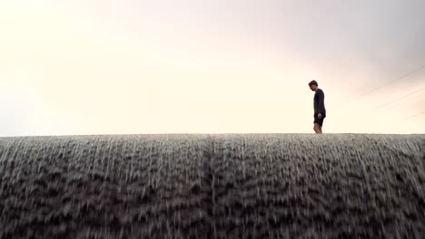 Man-walking-on-a-dam-in-Norway,-Europe-with-a-bright-background-and-a-beautiful-view-4K