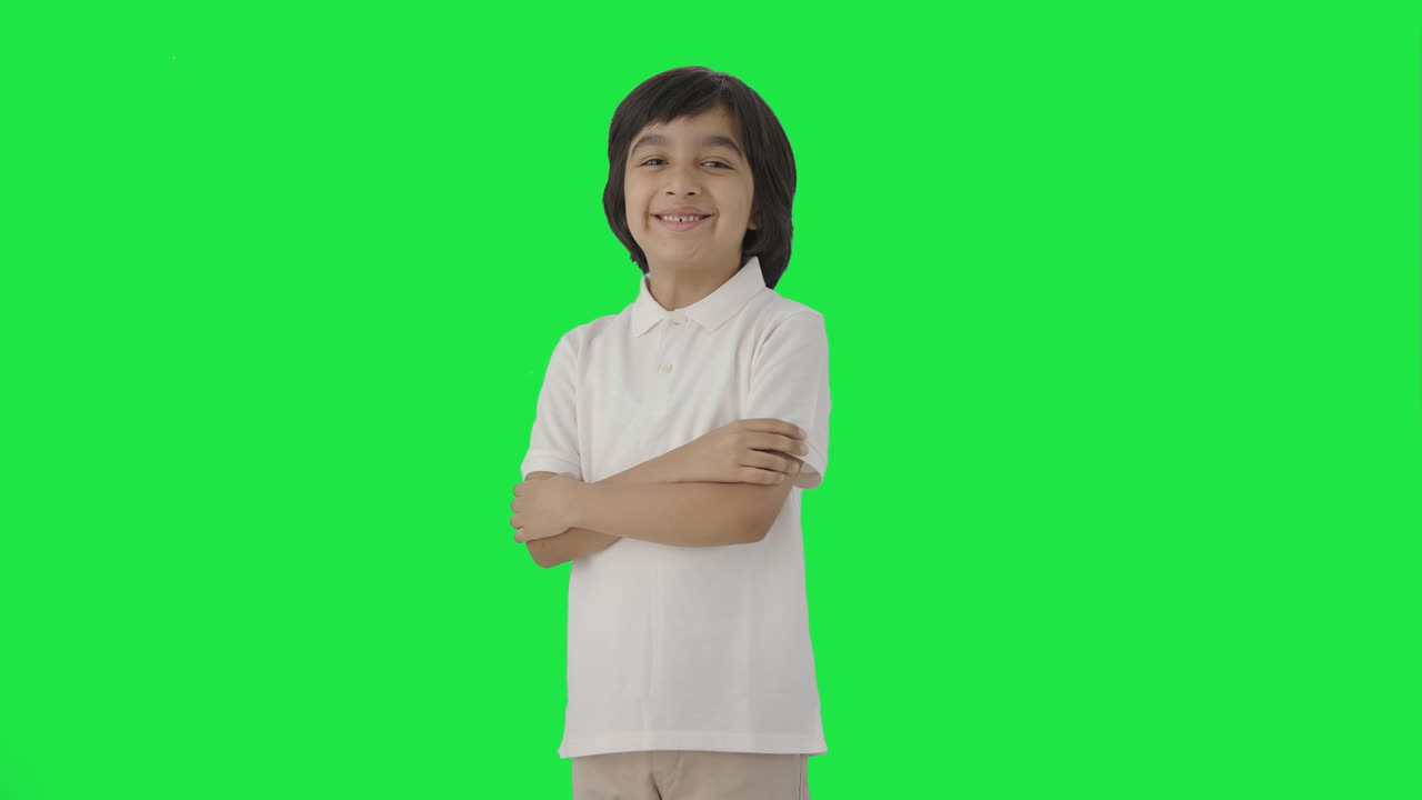 retrato de un niño indio feliz de pie con las manos cruzadas pantalla verde
