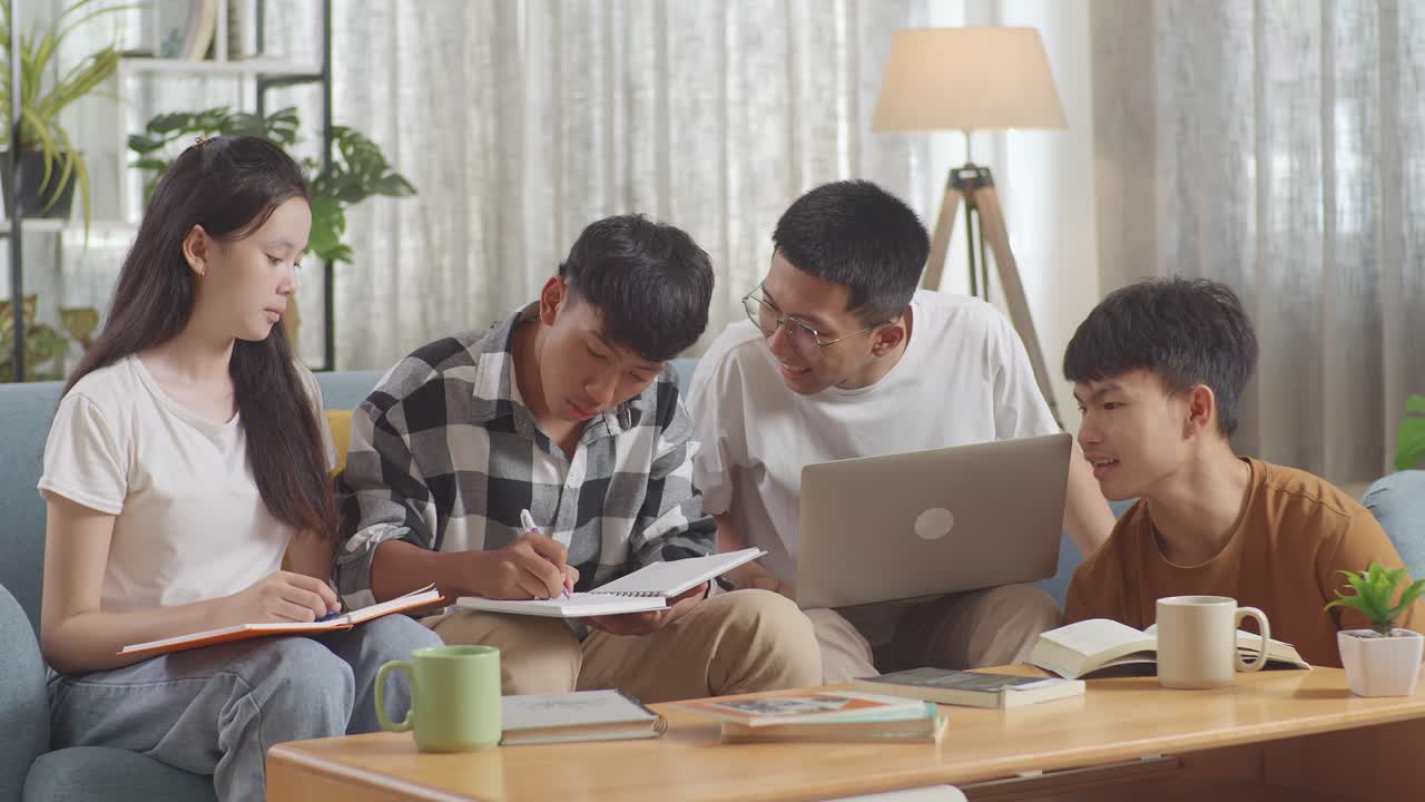 집에서 공부하는 아시아 십대 그룹: 노트북과 책을 가진 학생들이 노트북에 글을 쓰고, 프로젝트에서 성공을 축하하고, 하이파이브 제스처를 합니다.