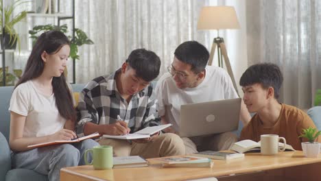 asian teen group studying at home. students with a laptop and books writing into notebook, celebrating success in project, giving high five gesture