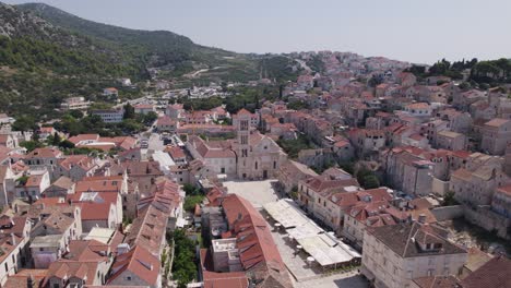 Aerial-orbit-of-dense-cityscape,-mountain-backdrop