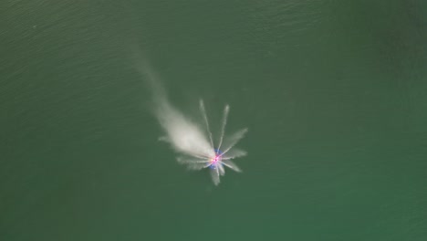 large fountain placed inside a lake pouring streams of thin lines of water on every side with a red and blue light inside waves around the lake peaceful location with calm atmosphere