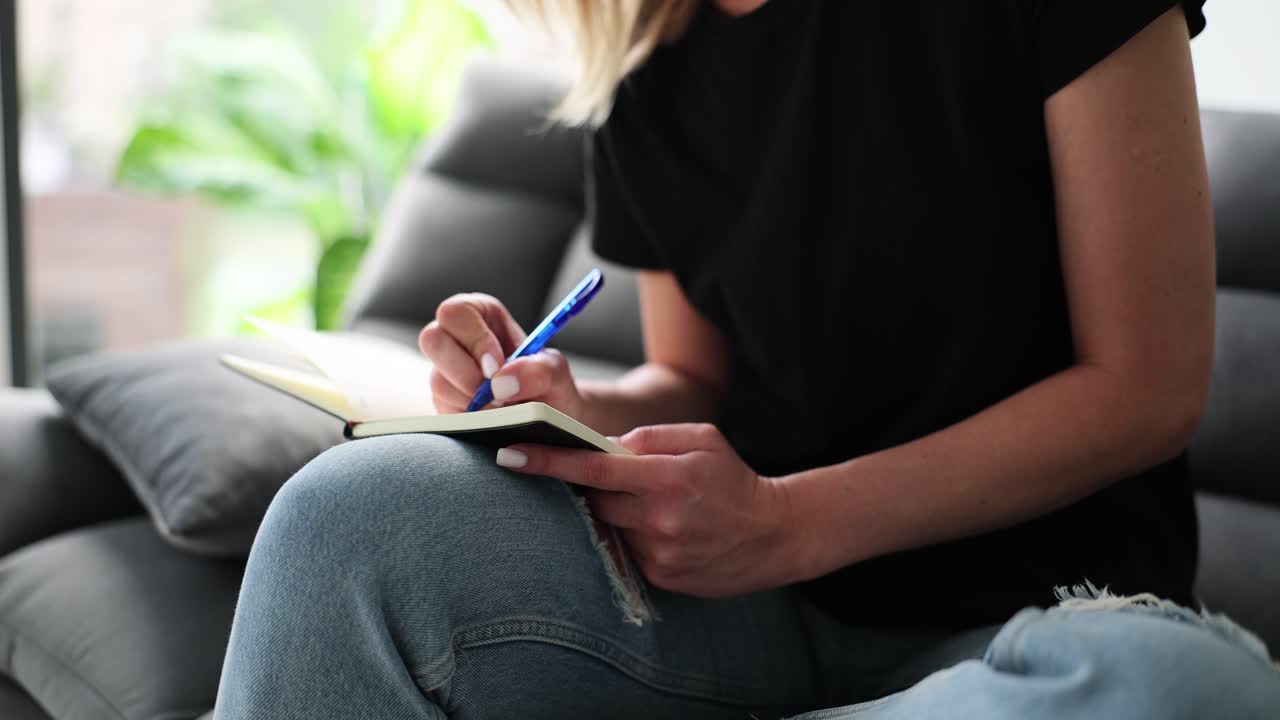 Woman freelancer writing weekly plan in notebook at home