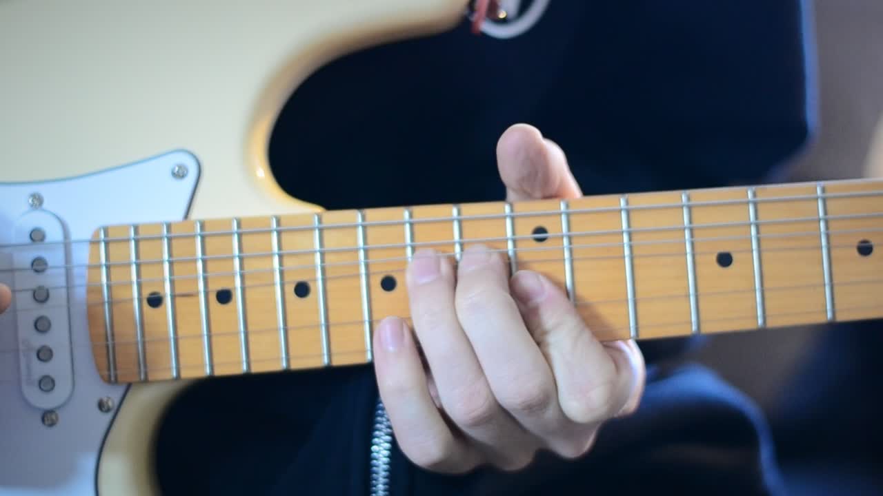 persona tocando un solo en una guitarra eléctrica blanca crema