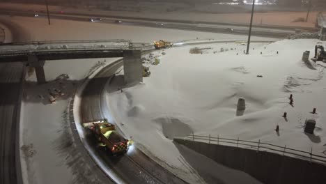 mississauga, canada - february 15, 2025: snow removal equipment clearing highway interchange during winter storm. heavy machinery operates on curved ramps and bridges amid fresh snowfall.