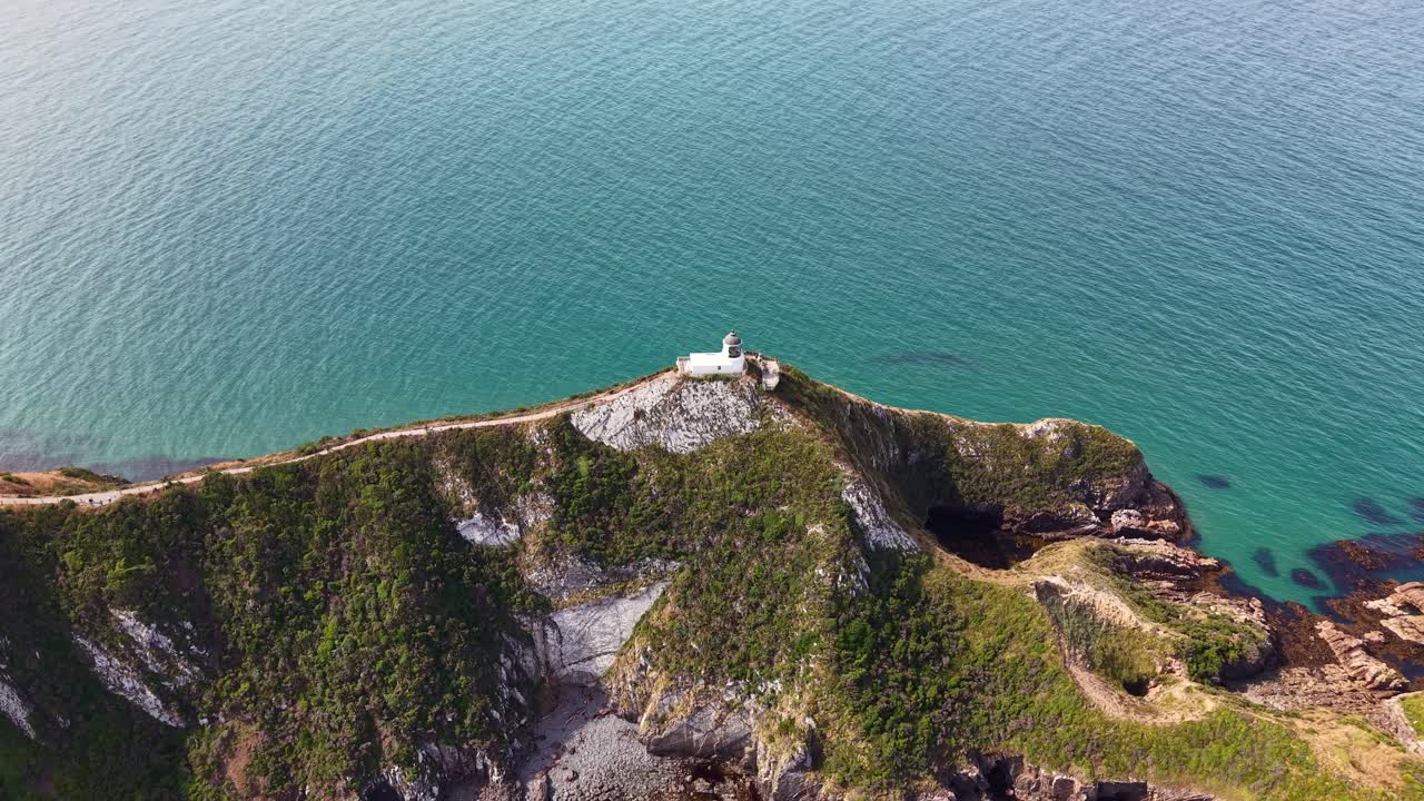 Drone orbiting 360 degrees around Nugget Point lighthouse with ocean backdrop