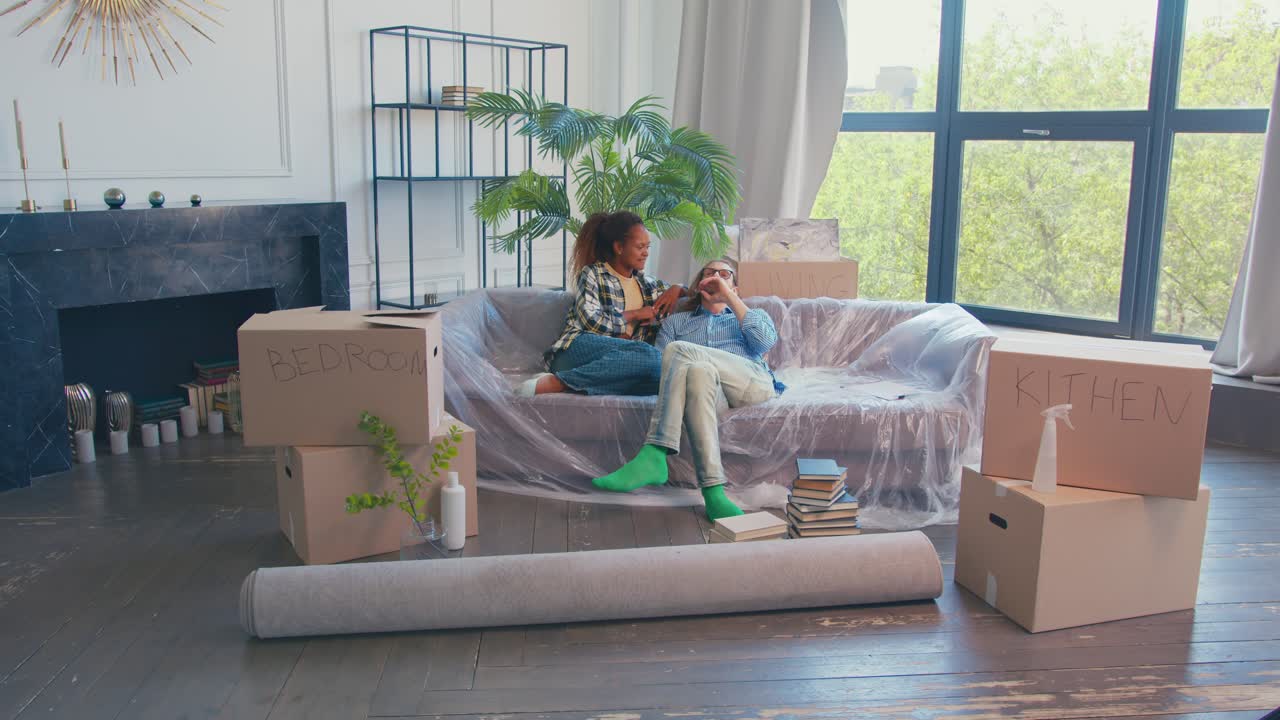 여성과 남성의 젊은 다인종 부부는 새로운 집으로 이사했습니다.