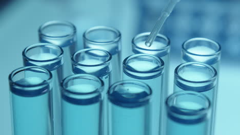dripping liquid chemical into test tubes with pipette in laboratory