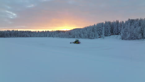 Seguimiento-Del-Soplador-De-Nieve-Del-Tractor-Norbotten-Borrado-De-La-Pista-De-Hielo-Del-Bosque-Bajo-La-Brillante-Vista-Aérea-Del-Amanecer