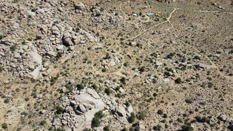 Small-building-surrounded-by-vast-desert-terrain-in-ascend-fly-over-view