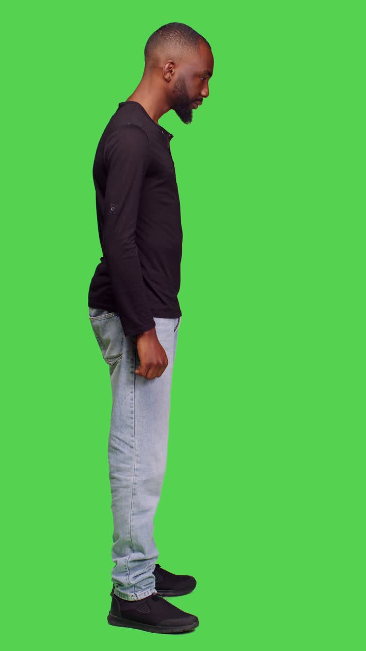 Vertical video: Profile of optimistic adult standing over green screen backdrop