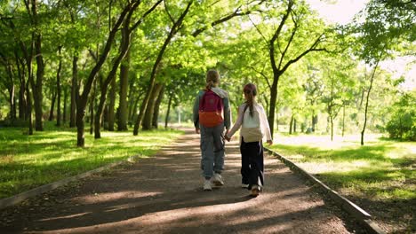 two girls walking hand-in-hand in a park