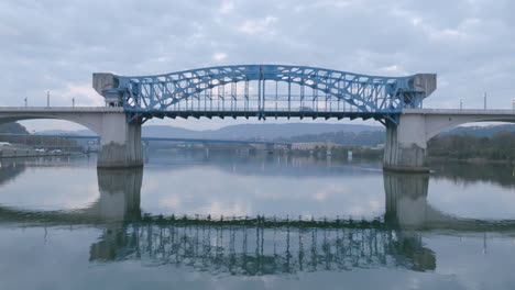 aerial footage during sunrise close to the water of the tennessee river going under the market street bridge