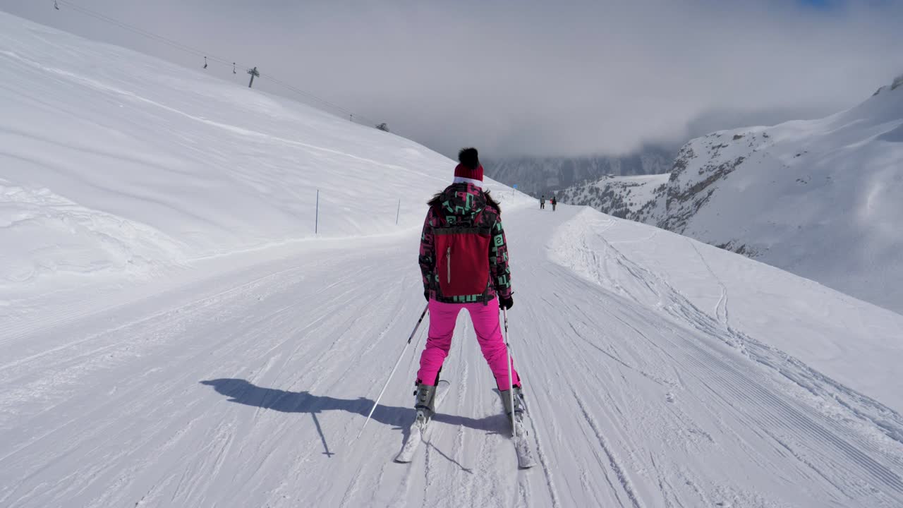 Sciaatrice che scende lentamente sulla pista da sci in montagna