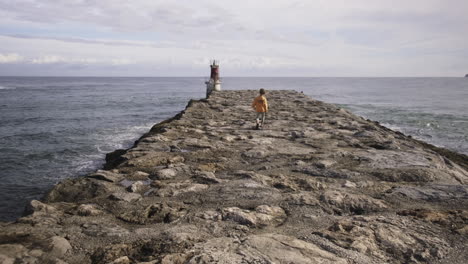 Young-boy-walking-towards-a-lighthouse-in-slow-motion