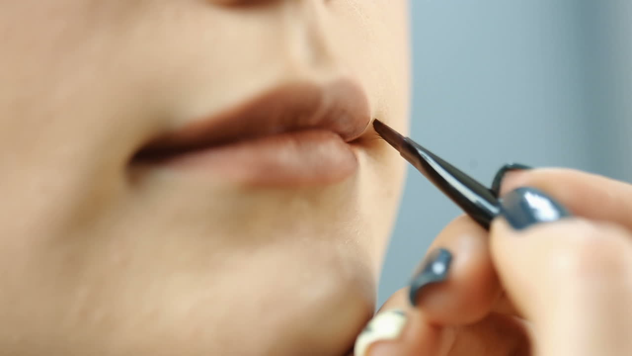 Girl applying lips. Makeup artist creating beautiful makeup for on her lips