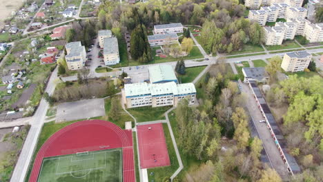 school building with basketball court and football stadium, aerial orbit view