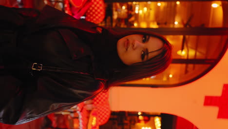 video vertical de una hermosa mujer joven mirando a la cámara, frente a un restaurante, en parís cerca de montmartre, por la noche