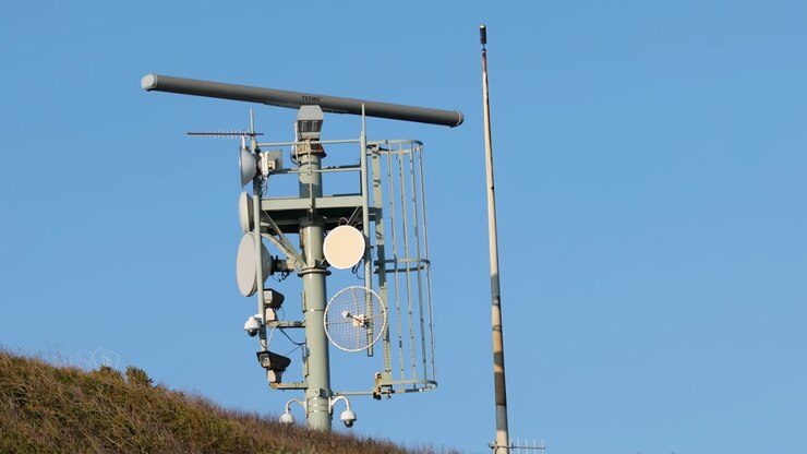 A rotating antenna system on a hill, set against a clear blue sky.