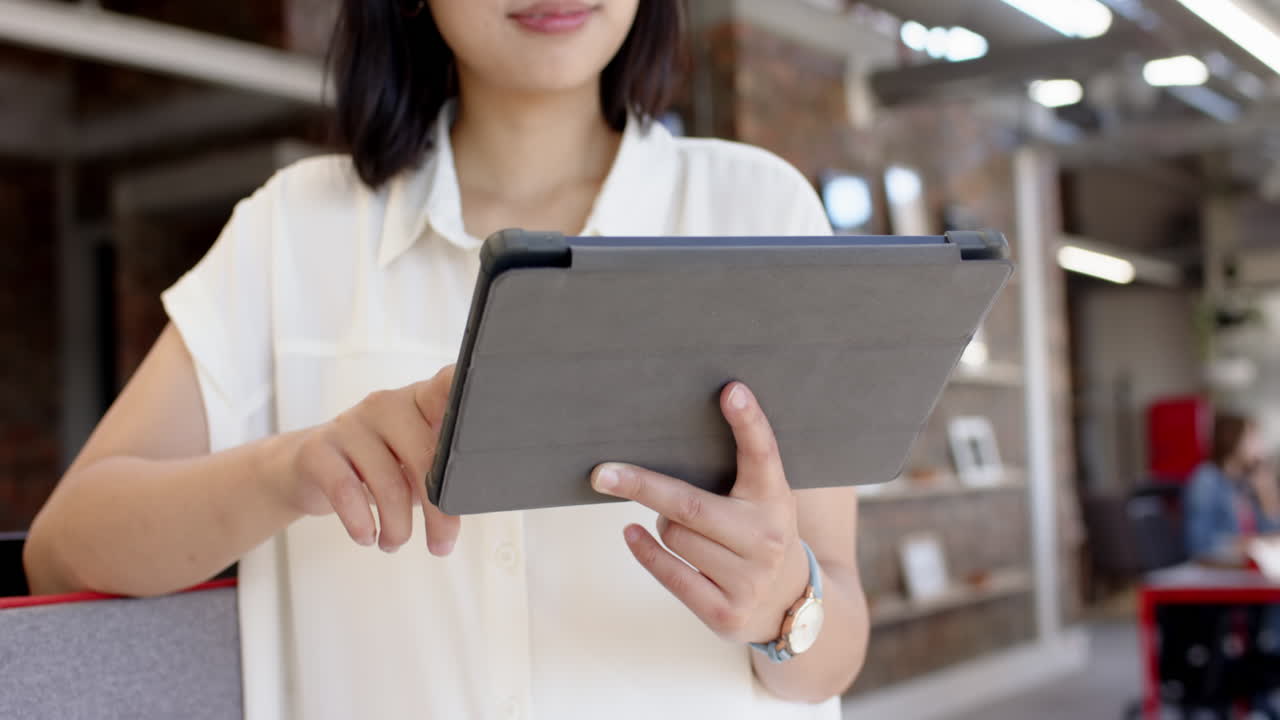 Using tablet, asian woman working on interior design project in modern office