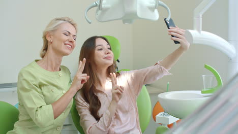 happy dentist and patient making selfie and showing v-sign. smiling doctor