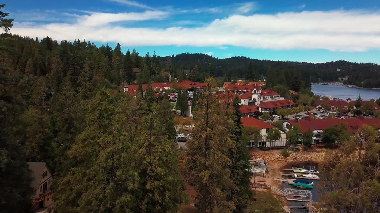 Flyover foreground treeline to reveal unique mountain village. 4K