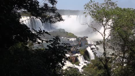 tourists on platform above iguacu river, at iguacu falls, brazil argentina border