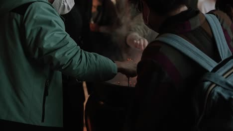 people placing incense sticks in pot at japanese temple