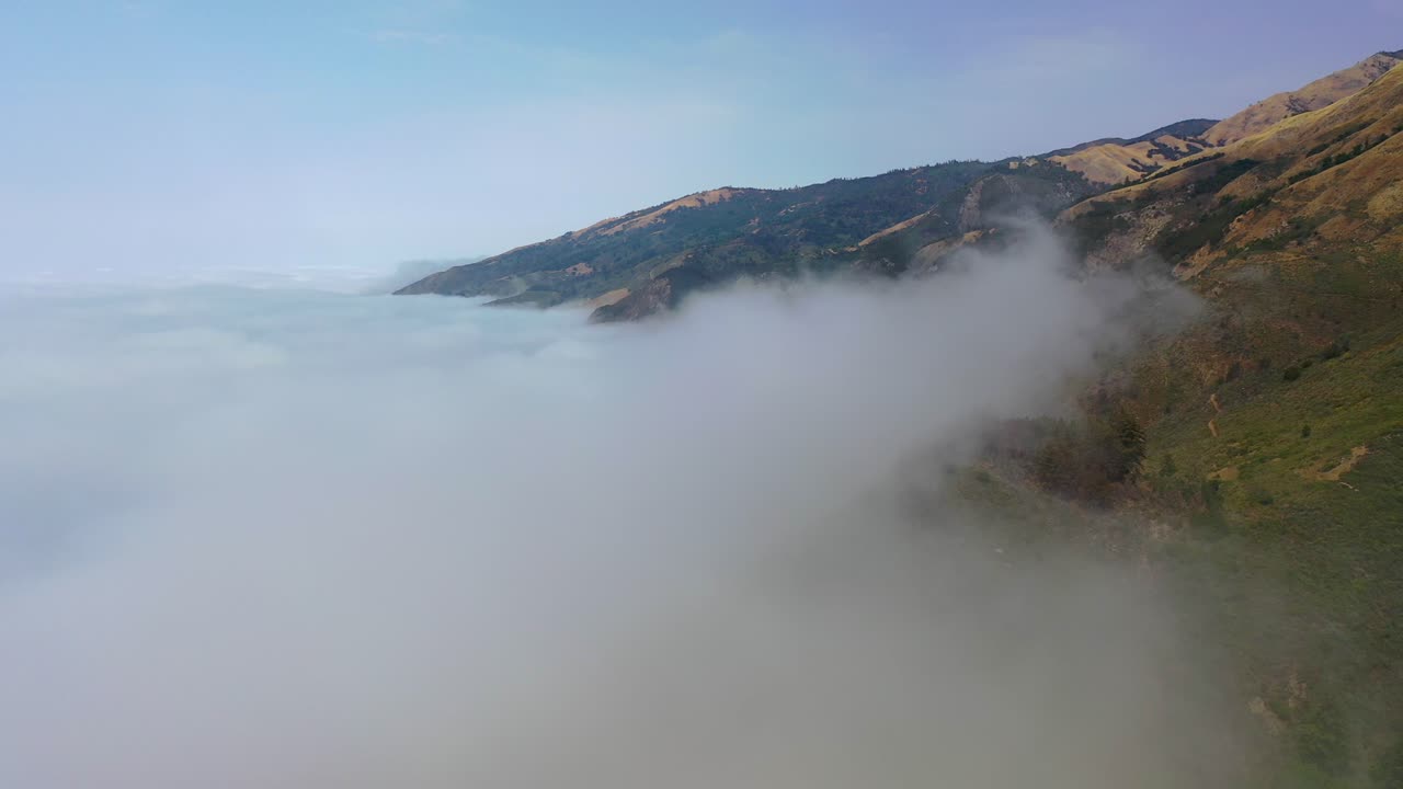 안개를 통해 아름다운 공중 촬영은 빅서 근처의 태평양 연안 고속도로를 따라 캘리포니아의 고속도로를 따라 외딴 산들을 보여줍니다.