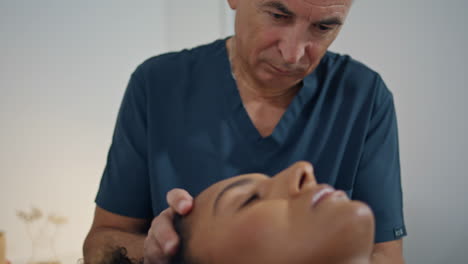 paciente de primer plano acostado fisioterapia en la sala del hospital hombre de cabello gris osteópata