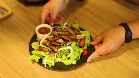 manos arreglando ensalada de cerdo con salsa