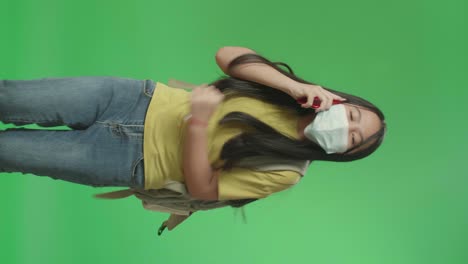 asian girl student wearing a mask and talking on mobile phone while running to school on green screen chroma key