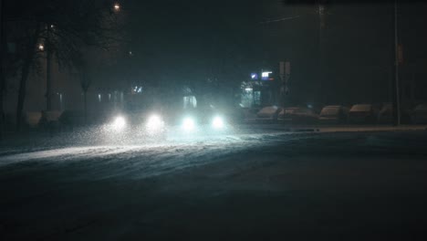 Cars-driving-in-the-city-on-a-frosty-winter-night,-during-a-blizzard,-super-slow-motion