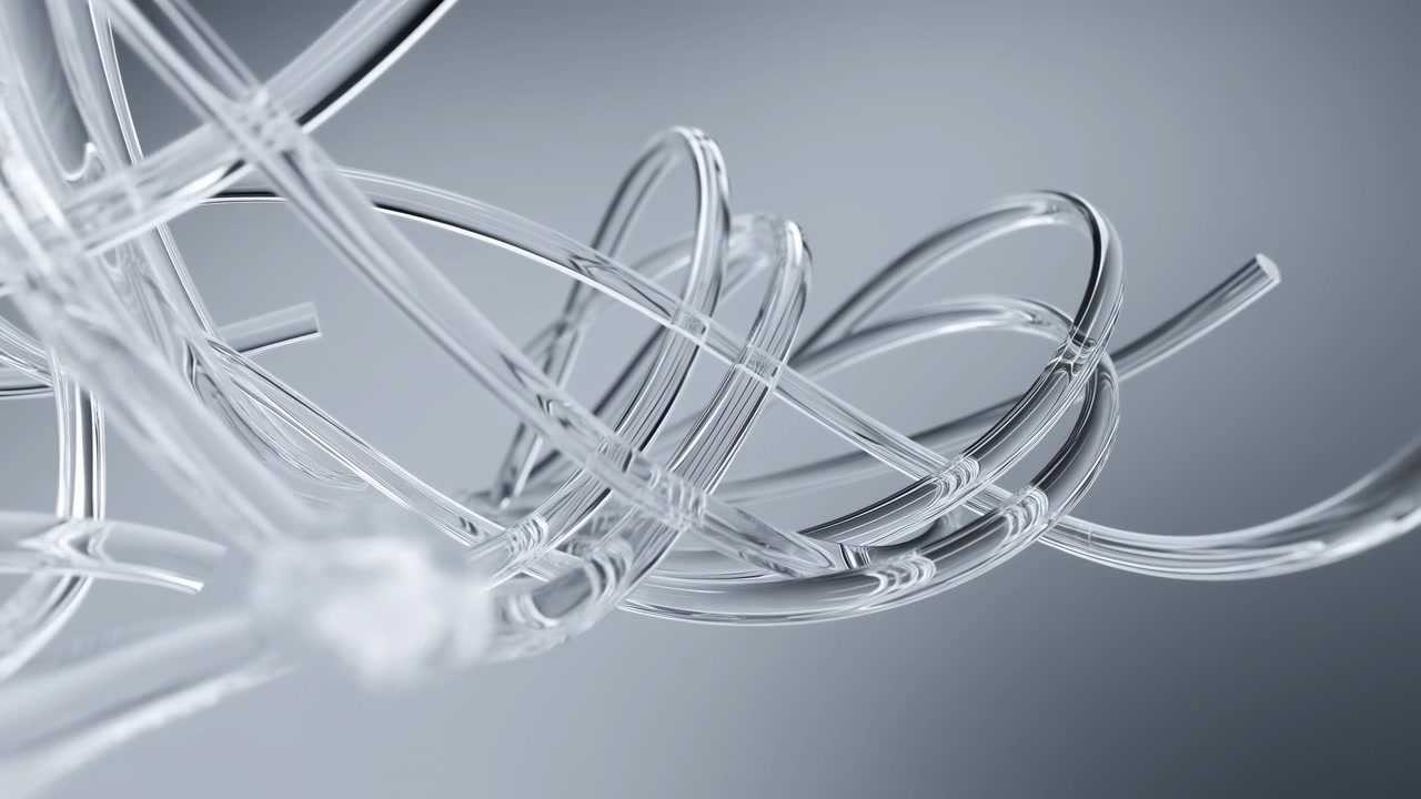 Clear rounded object travels diagonally down and left beside looping transparent forms, while bright reflections trace smooth curves against softly lit gray backdrop with layered depth.