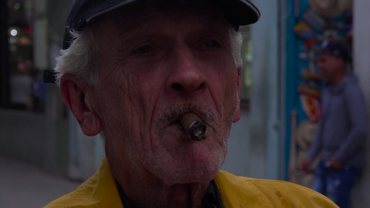 An old man smokes a cigar on the street in Havana Cuba