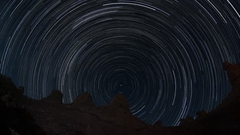 a timelapse of startrails over rocky pinnacle outcrops in the desert at night