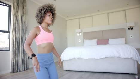 exercising in bedroom, woman stretching and wearing fitness tracker on wrist