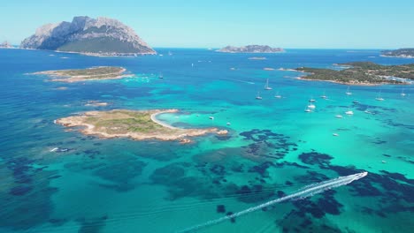 tavolara and cavalli island surrounded by boats and turquoise blue sea in sardinia, italy - aerial 4k