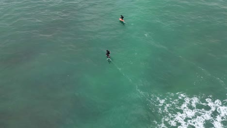 drone-captures-the-exhilarating-sight-of-men-sailing-on-electric-foil-boards,-skillfully-riding-waves-on-the-open-sea