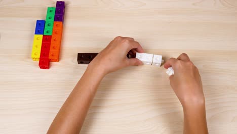 hands assembling cubes on a wooden table