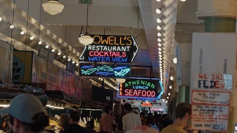 slow motion shot of the famous neon signs inside of the popular tourist attraction pike place market in seattle, washington where people go to buy goods and souvenirs