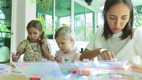madre e hijas creando joyas con cuentas