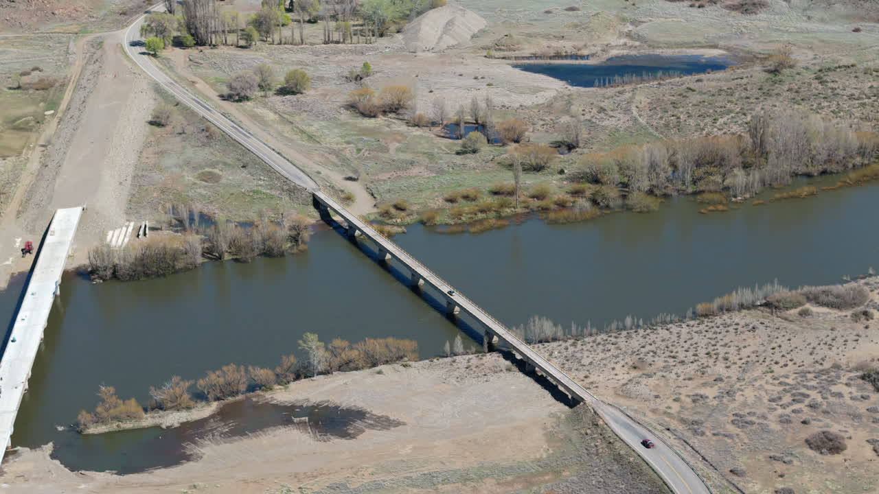 Drone descending Puente La Rinconada Bridge, vehicle crossing over Collon Cura River, Neuquen, Argentina