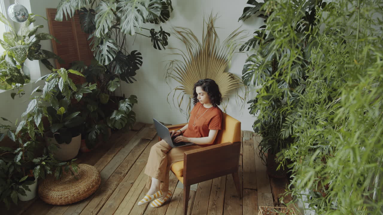 Menina Birracial Trabalhando no Laptop em Quarto com Plantas